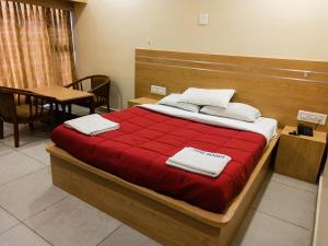 a bedroom with a bed with red sheets and white towels at Hotel Seagate in Velankanni