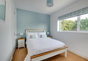 a white bedroom with a bed and a window at Berries in Woodbridge