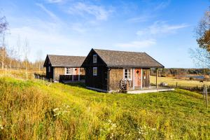 een klein zwart huis op een groen veld bij Ulvsby Ranch in Karlstad
