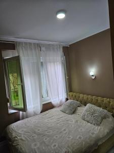a bed with two pillows in a bedroom with a window at Apartman Nana in Mostar