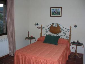 una camera da letto con un letto arancione e due tavoli di Casa Rural Cristina II a San Pablo de los Montes