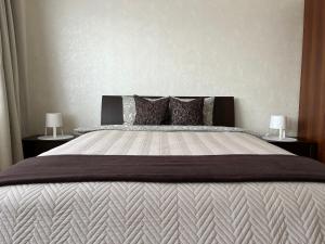a bedroom with a large bed with two lamps at Maxima apartments in Daugavpils