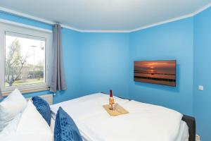1 dormitorio azul con 1 cama y TV en la pared en Möwen-Butze 8103 Yachthafenresidenz en Kühlungsborn