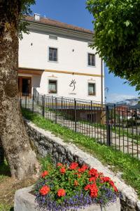 a building with a fence and flowers in front of it at Al Capriolo in Vodo Cadore