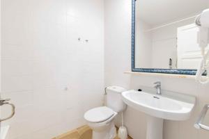 a white bathroom with a toilet and a sink at Siesta Mar Private Apartment 83 Cala'n Porter 1 bed in Cala'n Porter