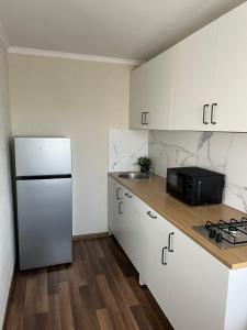 a kitchen with white cabinets and a refrigerator at Vienibas apartment in Daugavpils