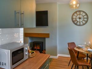 cocina con microondas y mesa con sillas en Hogarth Apartment By The Sea, en Newbiggin-by-the-Sea