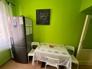 uma cozinha verde com uma mesa e um frigorífico em Family Friendly Apartman em Budapeste