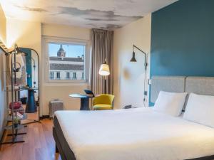 ein Hotelzimmer mit einem großen Bett und einem Fenster in der Unterkunft Ibis Malaga Centro Ciudad in Málaga