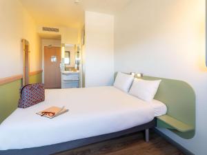Una cama en una habitación con un libro. en Ibis Budget Madrid Vallecas, en Madrid