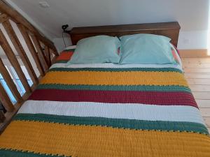 a bed with a colorful striped comforter and two pillows at Gîte Saint-Valéry-sur-Somme (gîte à la ferme) in Mons-Boubert