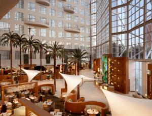 un hall d'un hôtel avec des palmiers et des tables dans l'établissement Hyatt Regency Orange County, à Anaheim