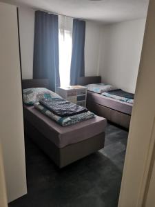 2 łóżka w małym pokoju z oknem w obiekcie Bob's Zimmer w mieście Bielefeld