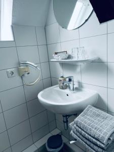 a white bathroom with a sink and a mirror at Hotel Stadt Boizenburg in Boizenburg