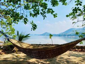 a hammock on a beach with a view of a lake at Ocamocam Beach Martins in New Busuanga