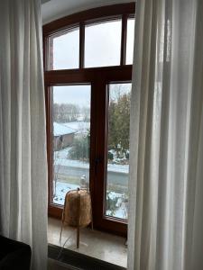 una ventana con vistas a un patio cubierto de nieve en Kuschelige Ferienwohnung auf Reiterhof, 