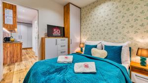 a bedroom with a blue bed with two towels on it at Apartament Kwisa - 5D Apartamenty in Świeradów-Zdrój