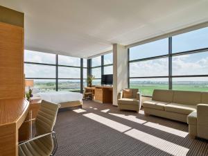 Habitación de hotel con cama, sofá y ventanas en Hyatt Place Amsterdam Airport, en Hoofddorp