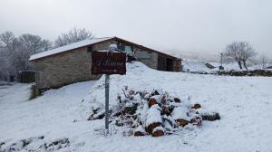 eine Herde von Tieren im Schnee neben einem Gebäude in der Unterkunft A Brava in Sas de Penelas