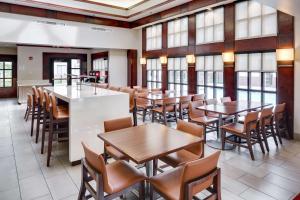 a dining room with tables and chairs and windows at Hyatt House Boston Waltham in Waltham