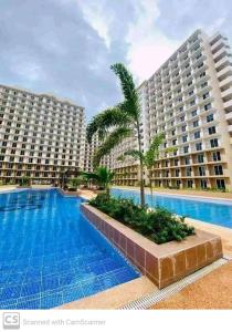 a large swimming pool in front of two large buildings at Adam&Eva Condo Staycation in Lapu Lapu City