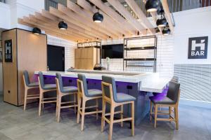 a bar in a restaurant with purple and gray chairs at Hyatt House Chicago Schaumburg in Schaumburg