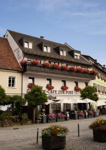 un grand bâtiment blanc avec des fleurs devant lui dans l'établissement Hotel Gasthof Zur Post, à Königstein in der Oberpfalz