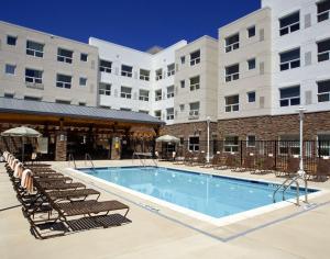 a pool in front of a hotel with lounge chairs at Hyatt House Boulder/Broomfield in Broomfield