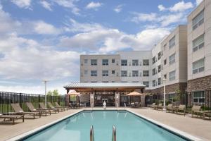 a hotel swimming pool with chairs and a building at Hyatt House Boulder/Broomfield in Broomfield