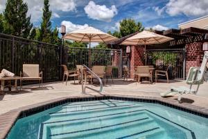 uma piscina com mobiliário de pátio e guarda-sóis em Hyatt House Branchburg - Bridgewater em Branchburg Park