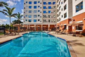 una gran piscina con sillas y un edificio en Hyatt House Fort Lauderdale Airport/Cruise Port en Dania Beach