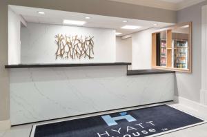 a lobby with a white marble wall with a large rug at Hyatt House White Plains in White Plains