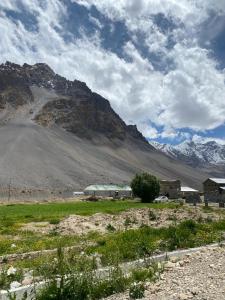 a building in a field with a mountain in the background at Moksha, Losar in Losar +10 photos