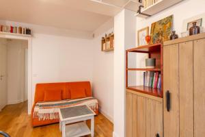 ein orangenes Bett in einem Zimmer mit Bücherregal in der Unterkunft Malakoff - Cosy appartement tout équipé aux portes de Paris in Malakoff