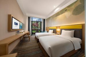 um quarto de hotel com duas camas e uma televisão em Holiday Inn Express Emei Mountain, an IHG Hotel em Emeishan