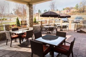 een patio met tafels en stoelen en een parasol bij Hyatt Place Charlottesville in Charlottesville
