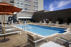 a hotel pool with chairs and an umbrella at Hyatt House Raleigh North Hills in Raleigh