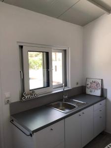 uma cozinha com um lavatório e uma janela em Studios on the beach em Galaxidi