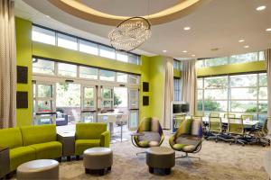 un vestíbulo con sillas verdes, mesas y ventanas en Hyatt House Seattle/Redmond, en Redmond