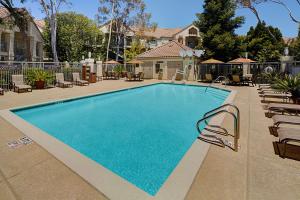 a large swimming pool with chairs and a fence at Hyatt House Belmont Redwood Shores in Belmont