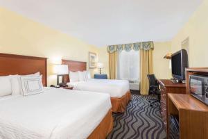 a hotel room with two beds and a flat screen tv at Baymont by Wyndham Savannah Midtown in Savannah