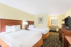 a hotel room with two beds and a flat screen tv at Baymont by Wyndham Savannah Midtown in Savannah