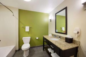 a bathroom with a toilet and a sink and a mirror at Sleep Inn & Suites in Colby