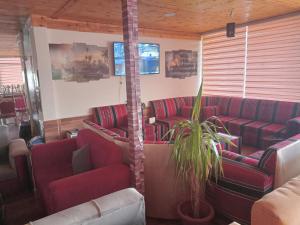 a waiting room with red couches and a plant at cabin hotel in Ma‘ān