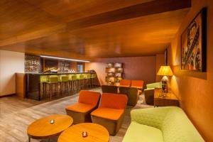 a restaurant with a bar with orange and green chairs at Hyatt Place Hyderabad Banjara Hills in Hyderabad