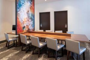 Hyatt Place Detroit/Royal Oak في رويال أوك: قاعة اجتماعات مع طاولة وكراسي خشبية