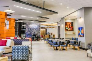 a waiting room with tables and chairs at Hyatt Place Greenville Downtown in Greenville