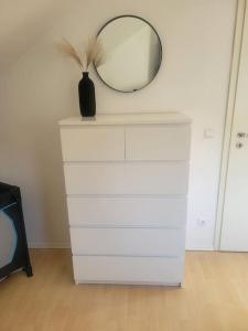 a white dresser with a mirror and a vase on it at Ruhige Ferienwohnung auf dem Land in Starzach