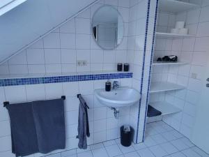 ein weißes Badezimmer mit einem Waschbecken und einem Spiegel in der Unterkunft Ruhige Ferienwohnung auf dem Land in Starzach