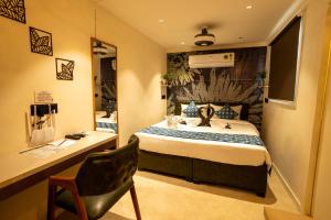 a bedroom with a bed with a desk and a chair at Click Hotel Mundra in Mundra
